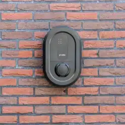 Ratio IO6 Pro laadpaal zwart met socket gemonteerd op bakstenen muur